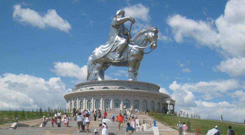 Silver Chinggis Khaan equestrian statue on its circular base, with visitors climbing the steps below, Tsonjin Boldog.