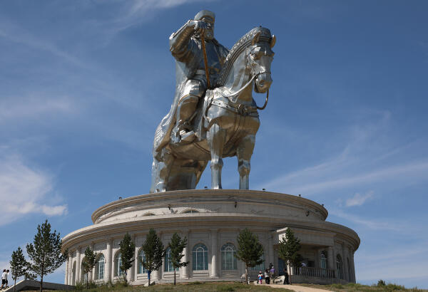 Large stainless-steel equestrian statue of Chinggis Khaan on top of a round visitor centre against a blue sky at Tsonjin Boldog