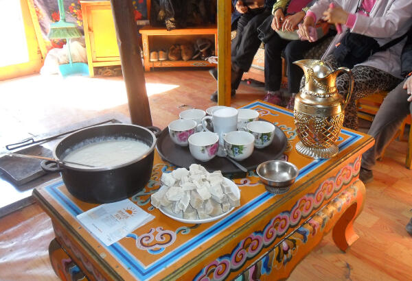Yogurt, dried curd and a brass jug on a painted table inside a nomadic family's ger.